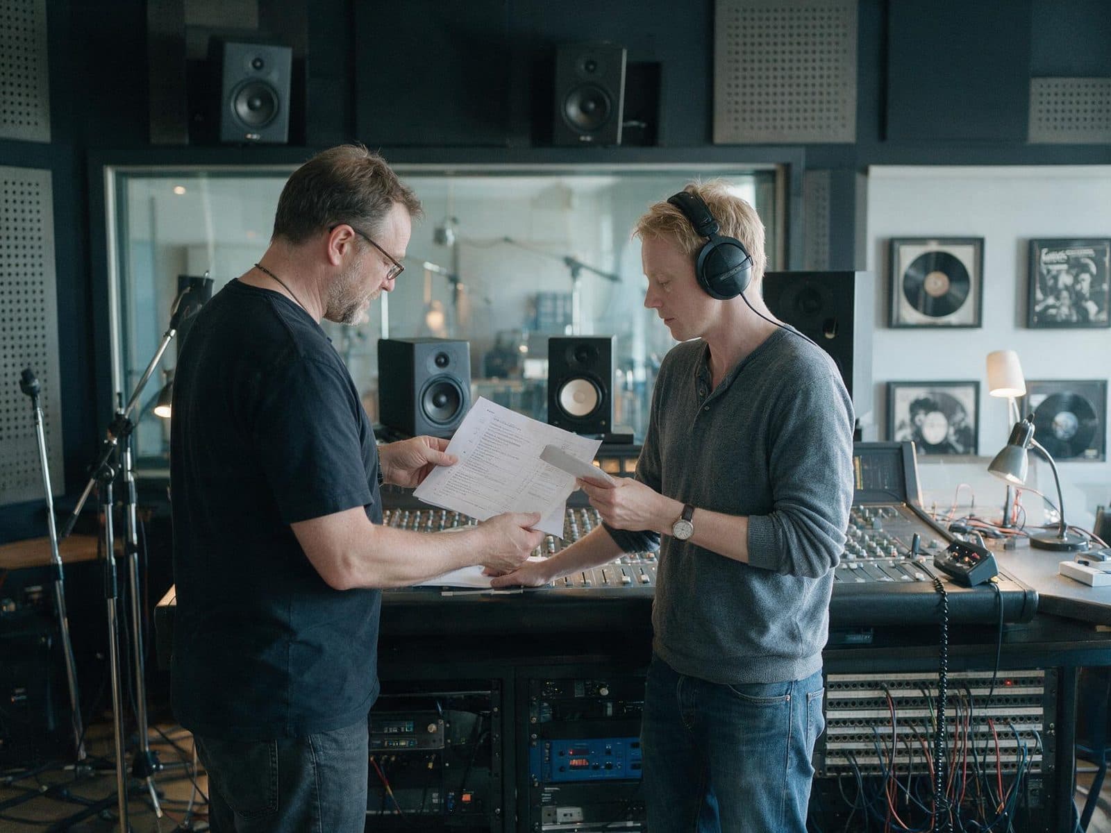 Producer and voice actor going through a script in the studio control room before a session