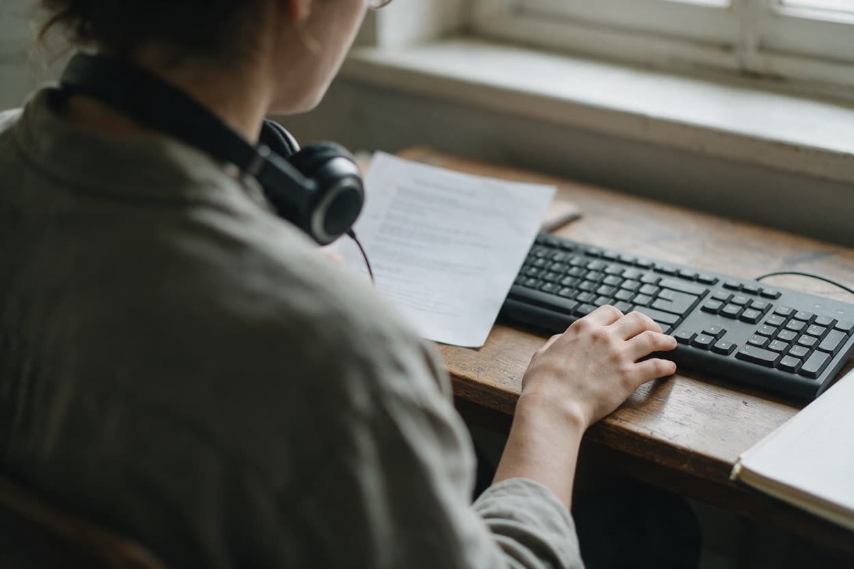 A linguist proofreading a printed transcript against the original recording