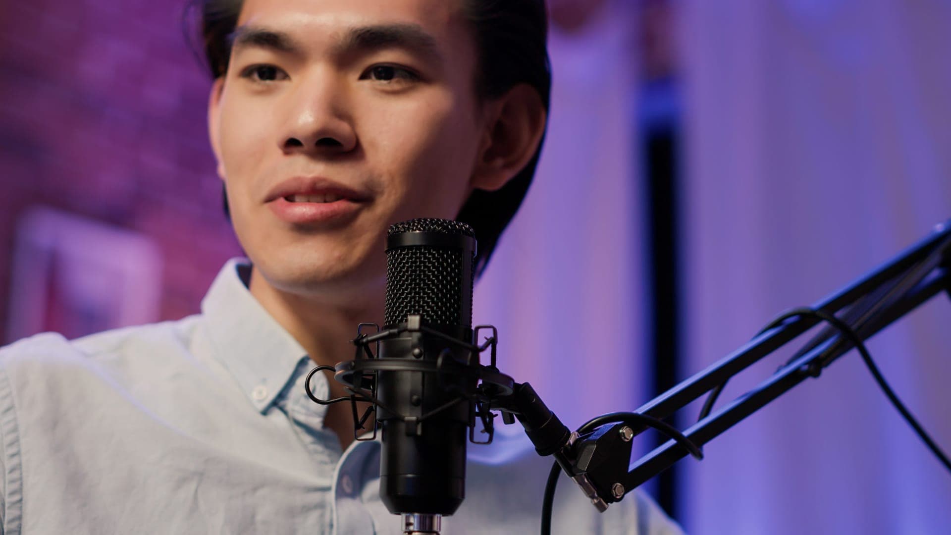 Asian presenter recording with a microphone