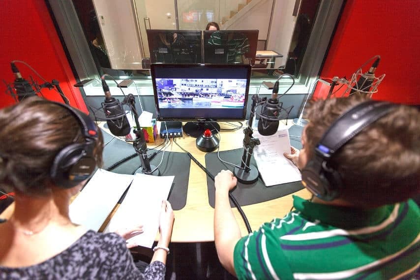 Two voice actors recording a radio commercial at microphones in GoLocalise's London studio