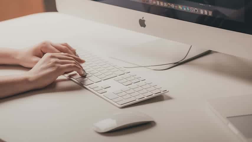 Picture illustrating a woman's hands typing on a keyboard in front of a computer. Retrieved from Unspalsh. For blog post English Subtitles and Differences In Spoken and Written Language.