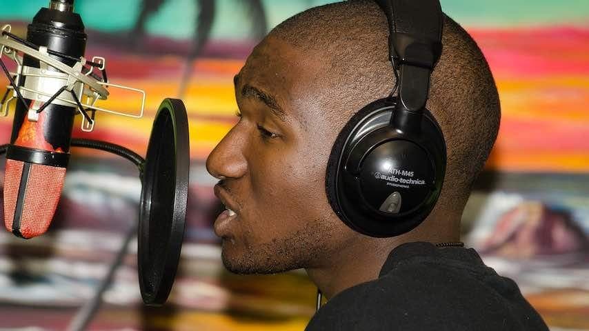 Black person recording vocals in a studio