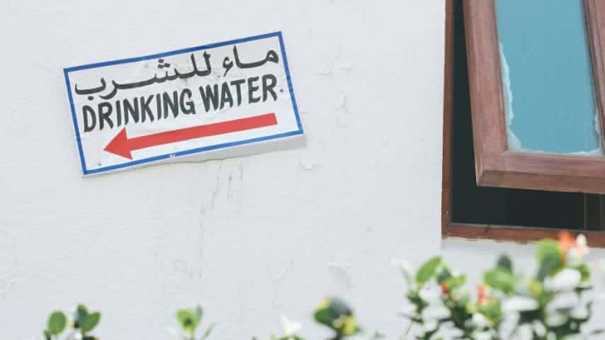 How to Translate English to Arabic Audio and Video. Sign on a wall saying "drinking water" in English and Arabic. Photo by Olivia Hutcherson at Unsplash. Unsplash License. https://unsplash.com/es/fotos/7to7gDInYns