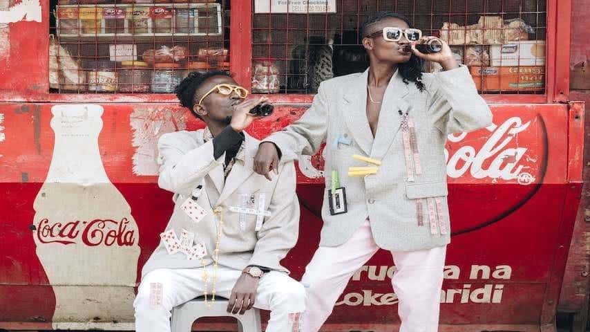 How Much do TV Commercials Cost. Image of two people drinking Coca Cola next to a kiosk. This image is used to illustrate the article "How Much do TV Commercials Cost?". Pexels license: https://www.pexels.com/photo/two-person-drinking-coca-cola-next-to-a-kiosk-1300576/