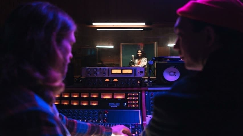 A sound engineer and director directing a voice-over artist in the studio