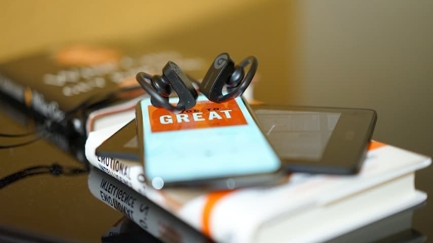 Unabridged Audiobook. Image of book with a tablet, smartphone and earphones. This image is used to illustrate the article "Abridged vs Unabridged Audiobooks: Which One Should You Choose?". Unsplash license: https://unsplash.com/photos/2ALQUTD5MKc