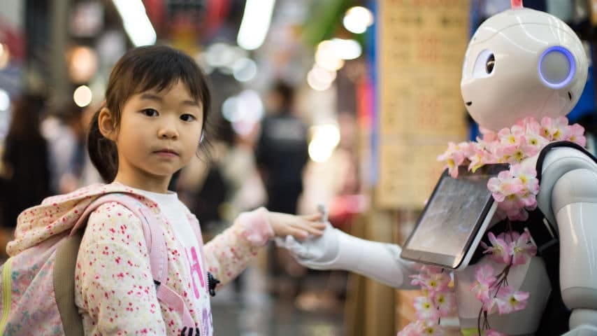 A little girl giving her hand to a robot