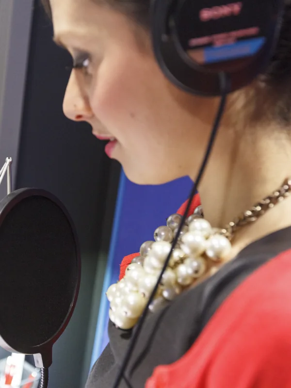 Voice artist performing at the microphone behind a pop shield
